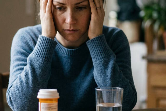 אישה מודאגת ליד כדור תרופה וכוס