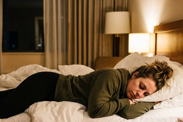 אישה ישנה במלון על המיטה